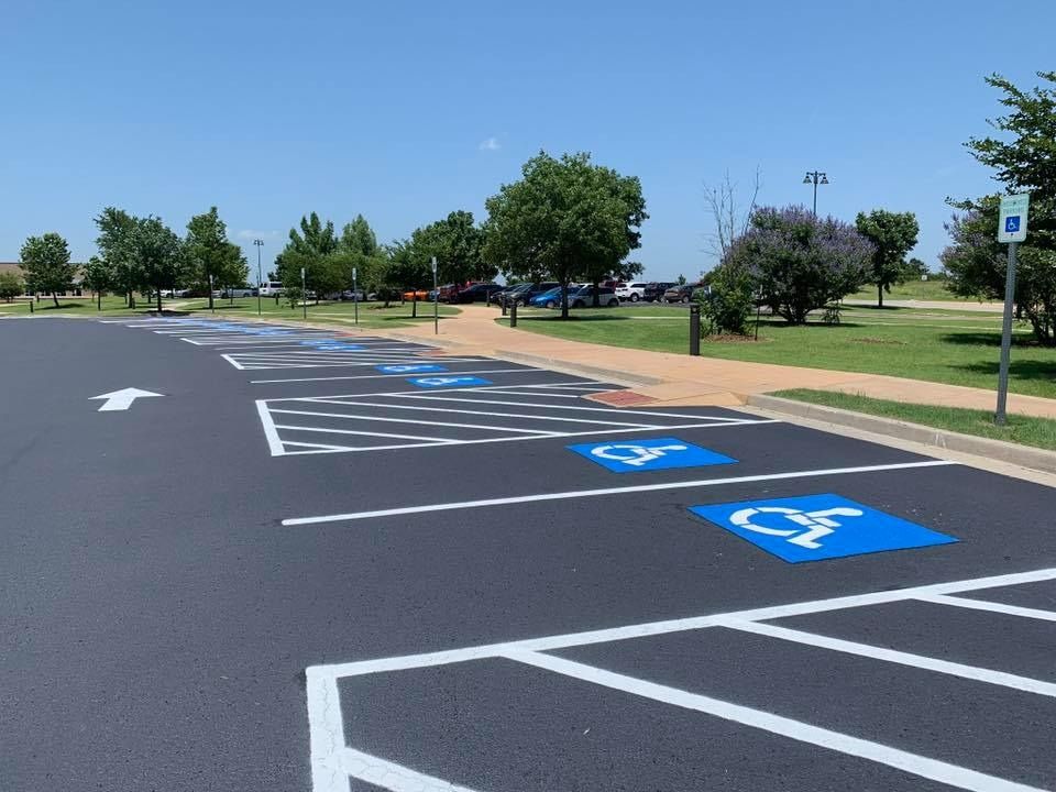 Empty parking lot with blue handicapped spaces and white directional arrows under a clear sky