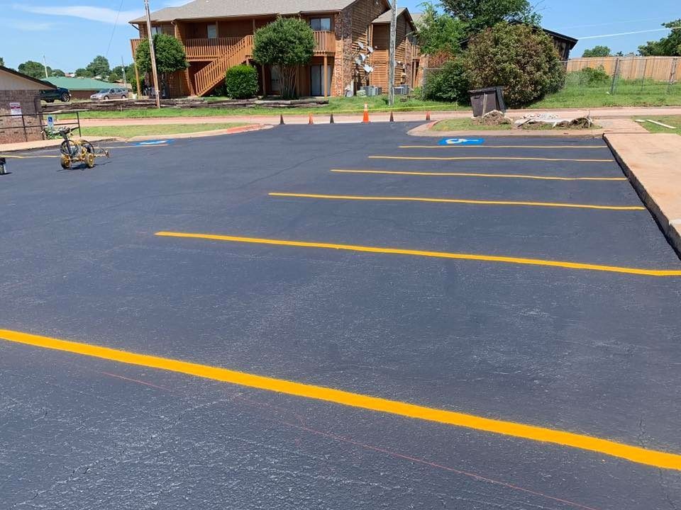 Empty asphalt parking lot with yellow lines and a building in the background