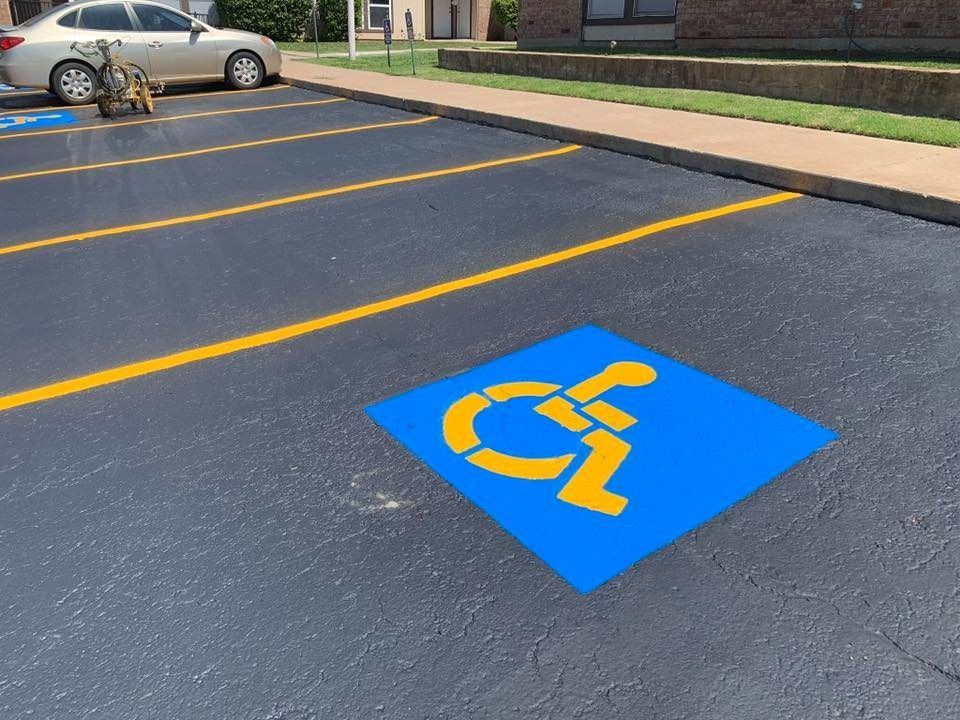 Accessible parking space marked with blue wheelchair symbol and yellow lines in a parking lot