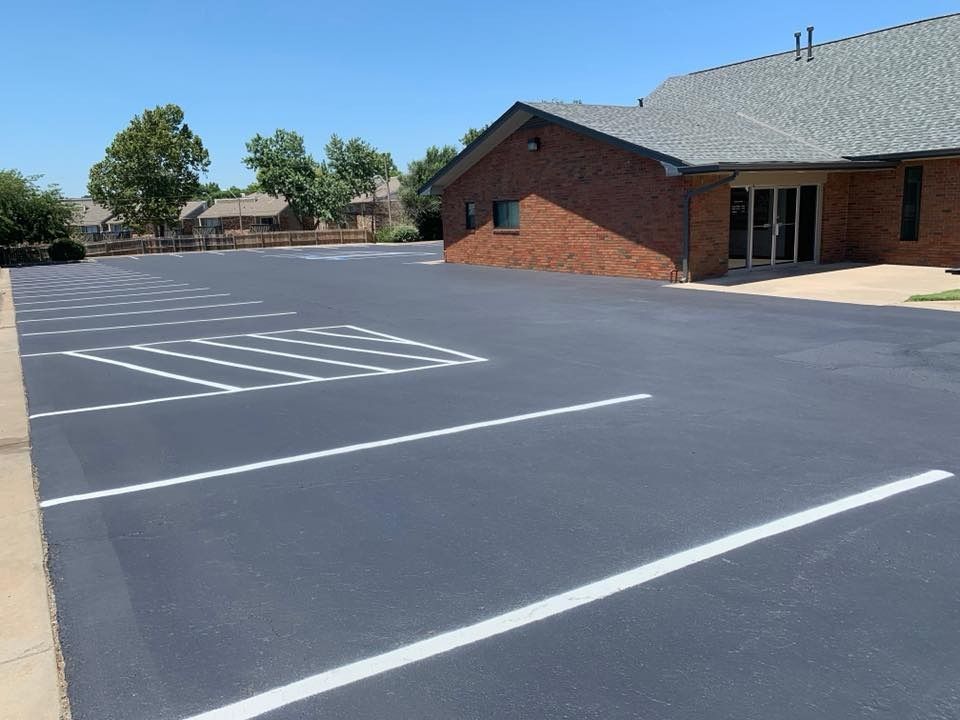 Empty paved parking lot beside a brick building on a sunny day