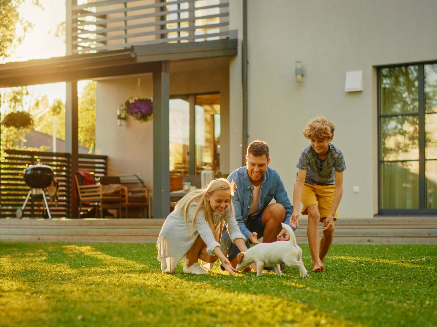 Pest control worker in protective suit spraying a wall in a room; the worker uses a tank sprayer.