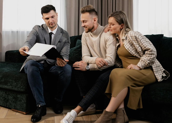 Real estate agent showing a contract to a couple on a sofa.