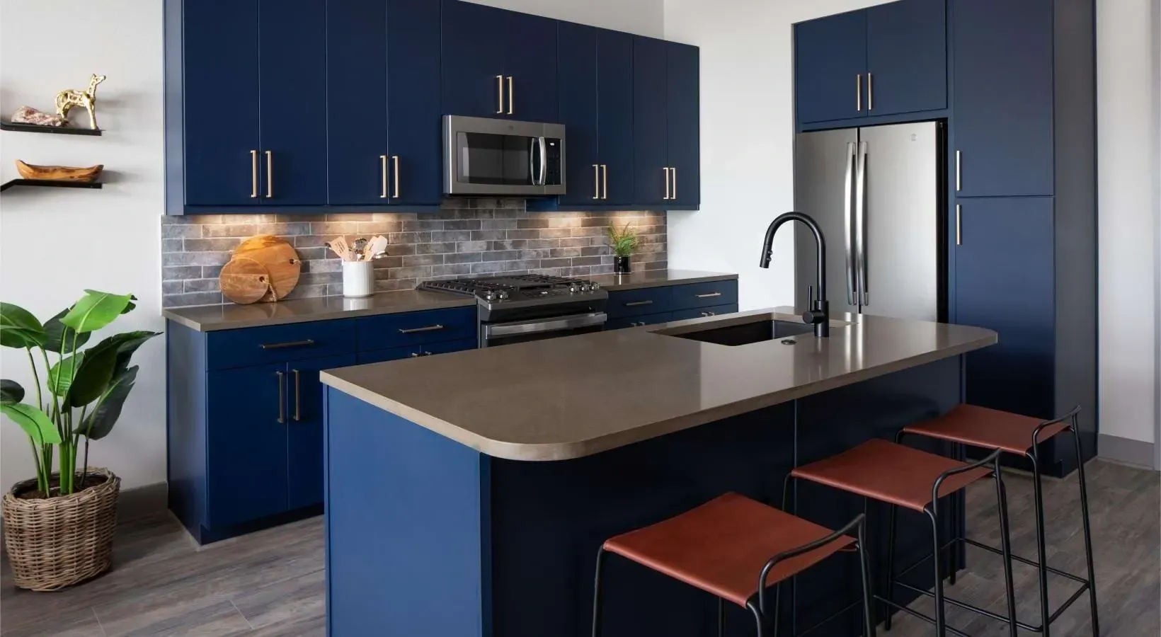 Modern kitchen with dark blue cabinets, stainless steel appliances, and a large island with bar stools.