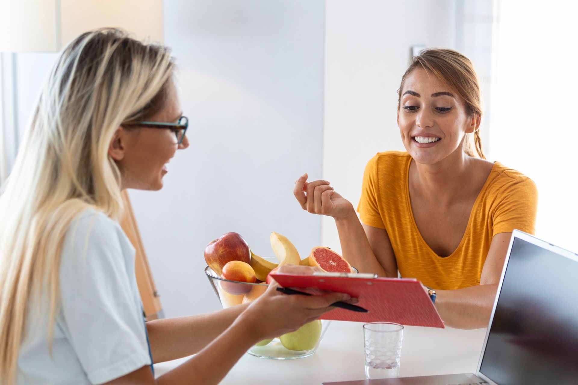 A woman is sitting at a table talking to a female nutritionist.