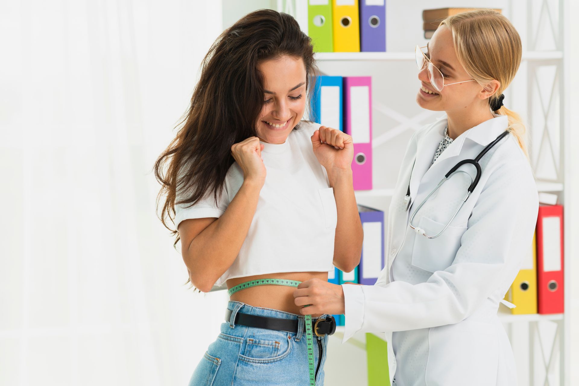 A doctor is measuring a woman 's waist with a tape measure.