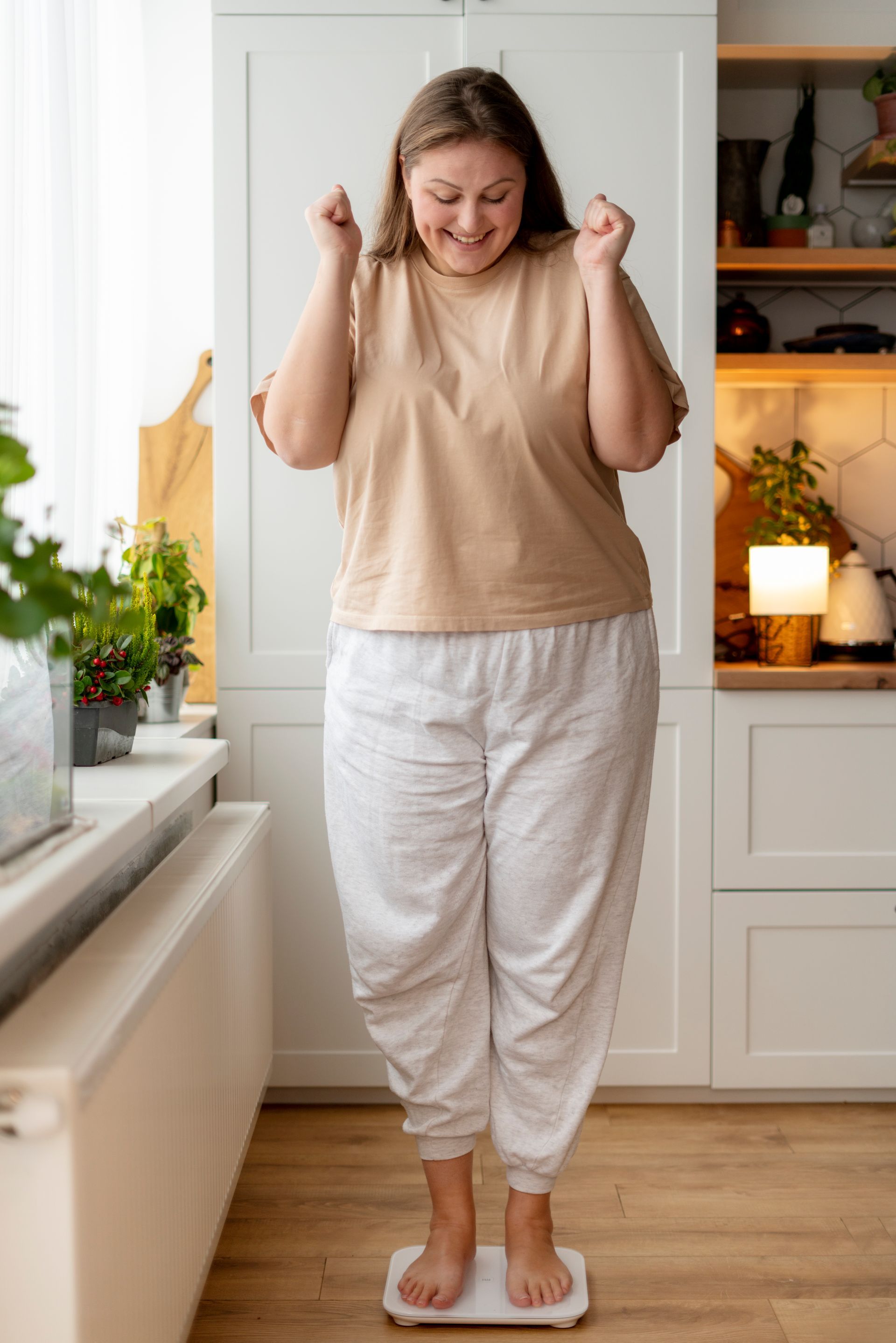 A woman is standing on a scale in a kitchen.