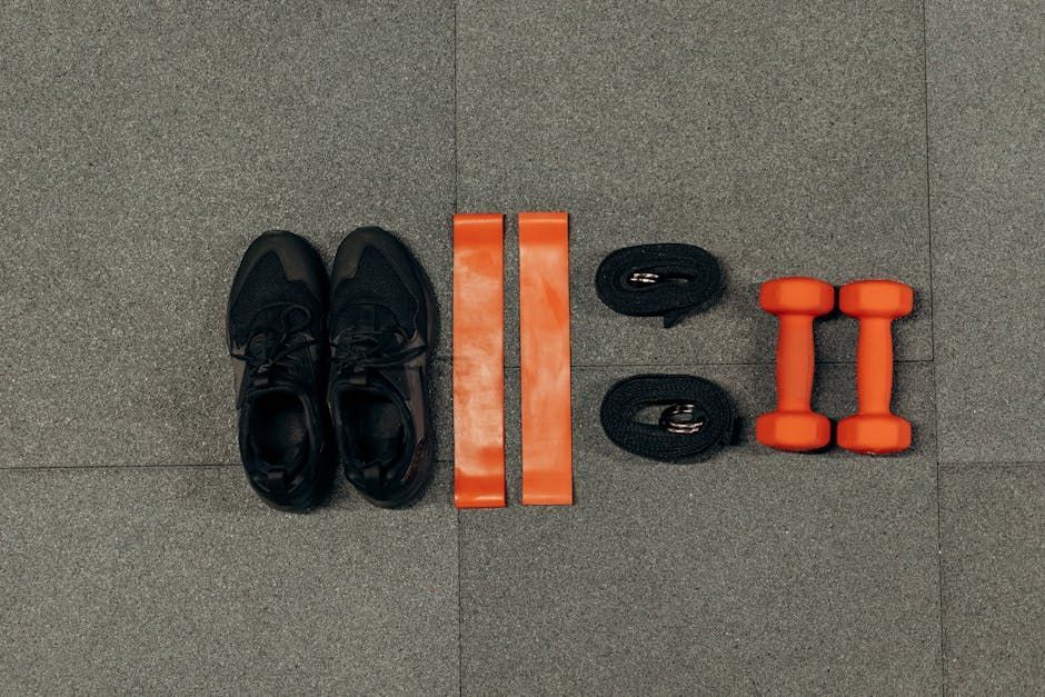Picture of gym equipments like sneakers, resistant bands and orange dumbbells