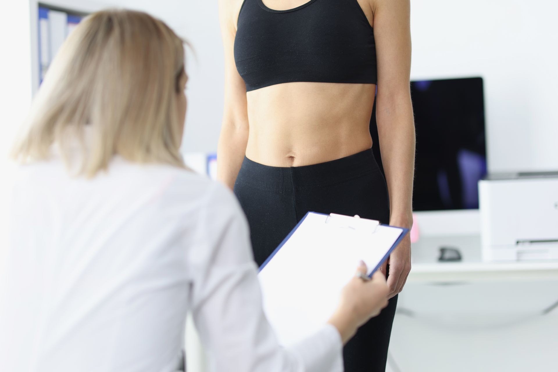 A woman is being measured by a doctor with a tape measure.