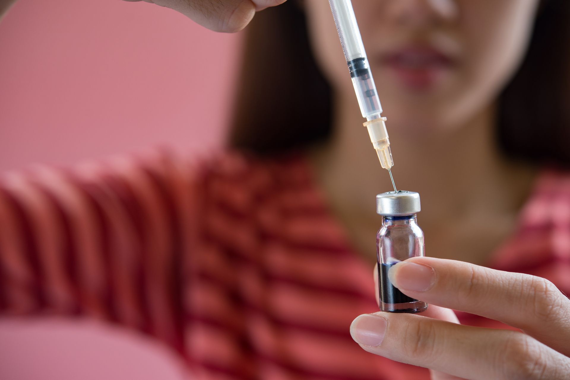 A woman is holding a syringe and a bottle of liquid.