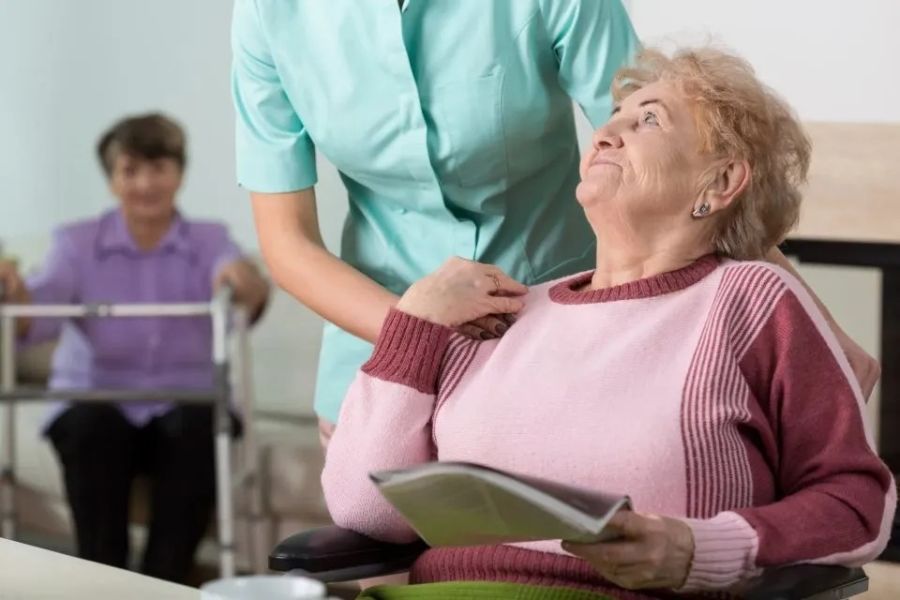 Donna anziana con infermiera porge la mano sulla sua spalla