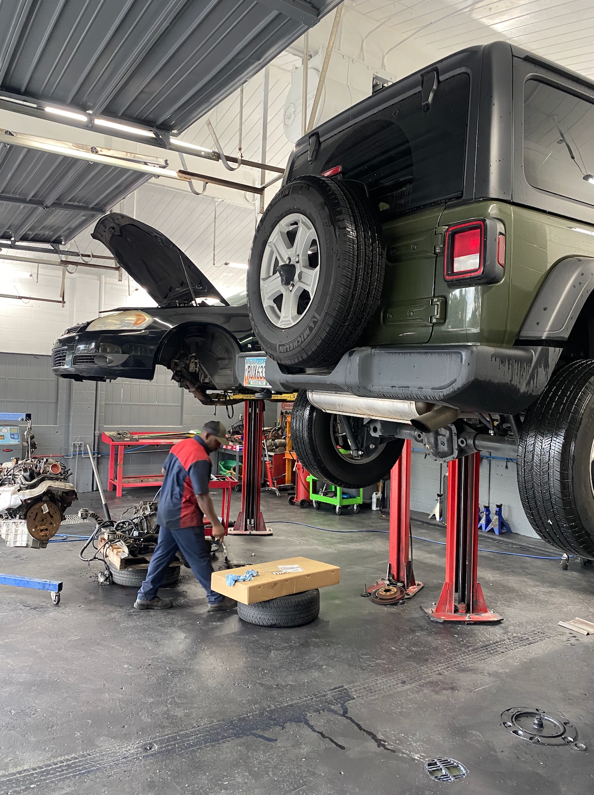 A man is working on a jeep in a garage.