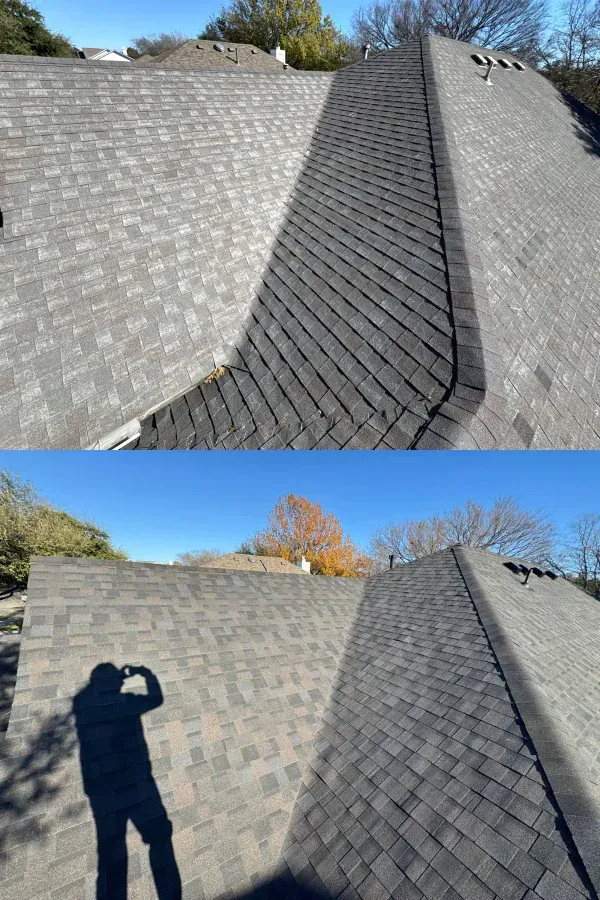A man is standing on top of a roof taking a picture.