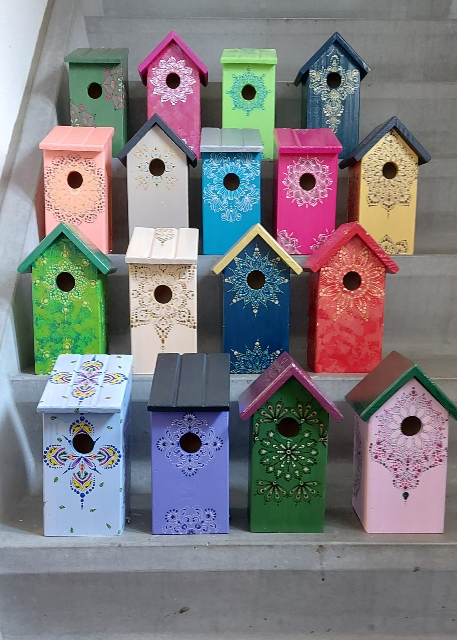 Kleurrijke, decoratieve vogelhuisjes op de trap. Elk huisje is in een andere kleur geschilderd 