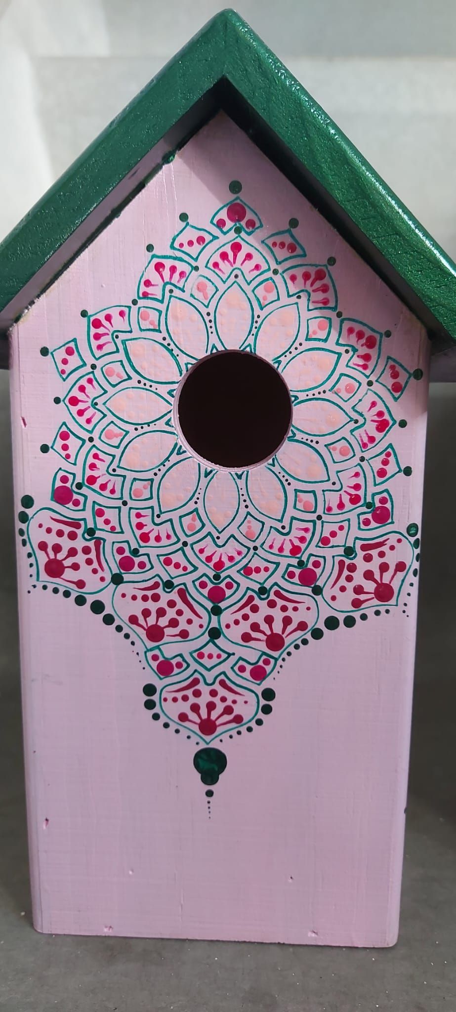 Roze vogelhuisje met groen glitterdak en ingewikkeld bloemenpatroon.