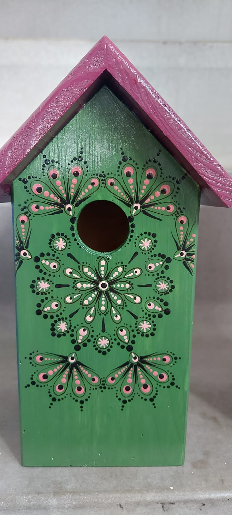 Groen vogelhuisje met paars dak en ingewikkeld bloemmotief.