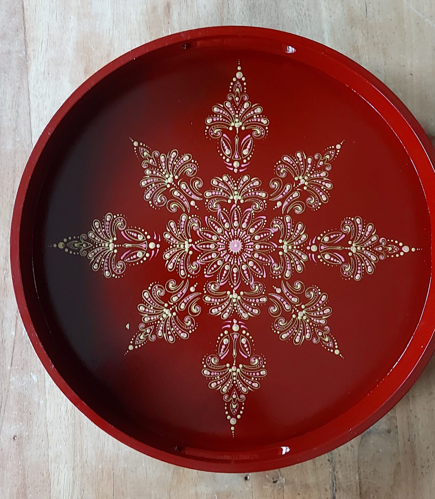 Rode, ronde serveerschaal met een gouden sneeuwvlokmotief.
