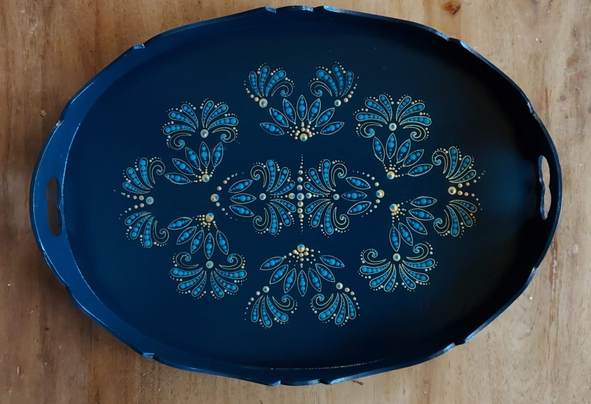 Donkerblauwe ovale schaal met een bloemmotief in turquoise en goud.