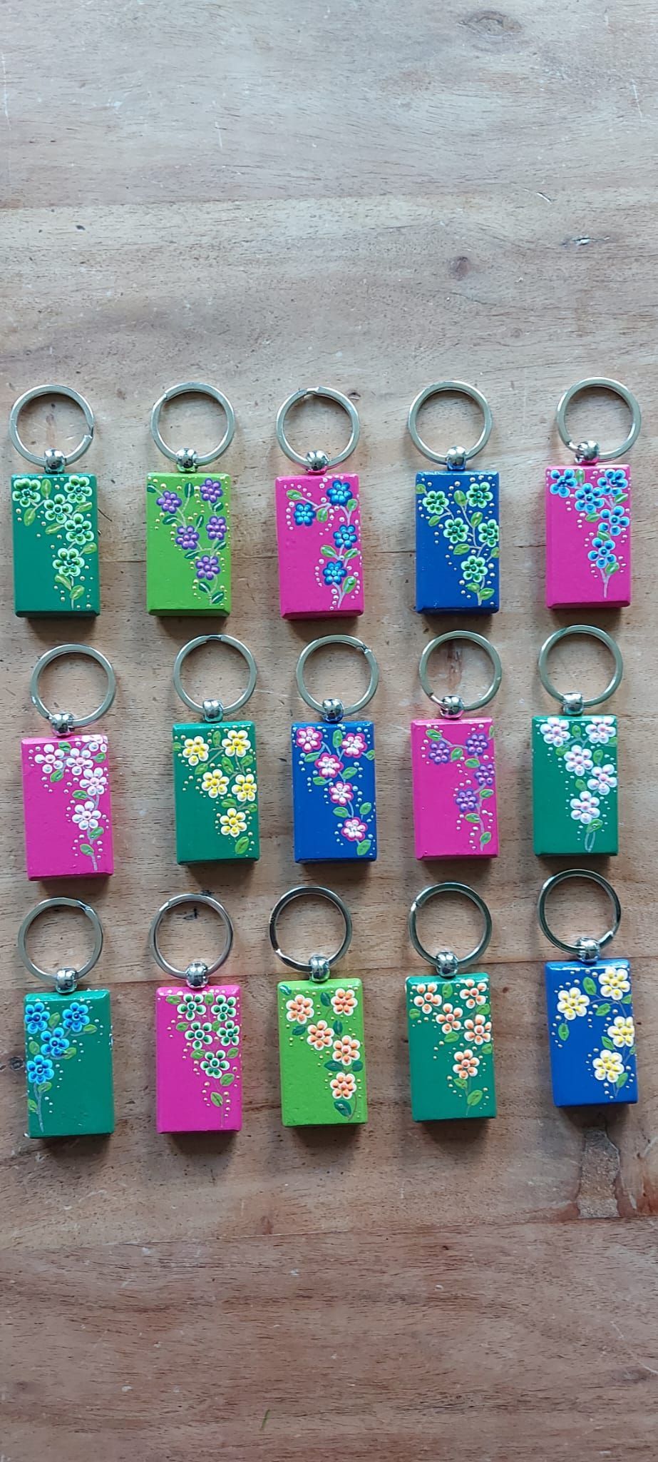 Sleutelhangers in diverse kleuren met bloemmotieven op een houten oppervlak.