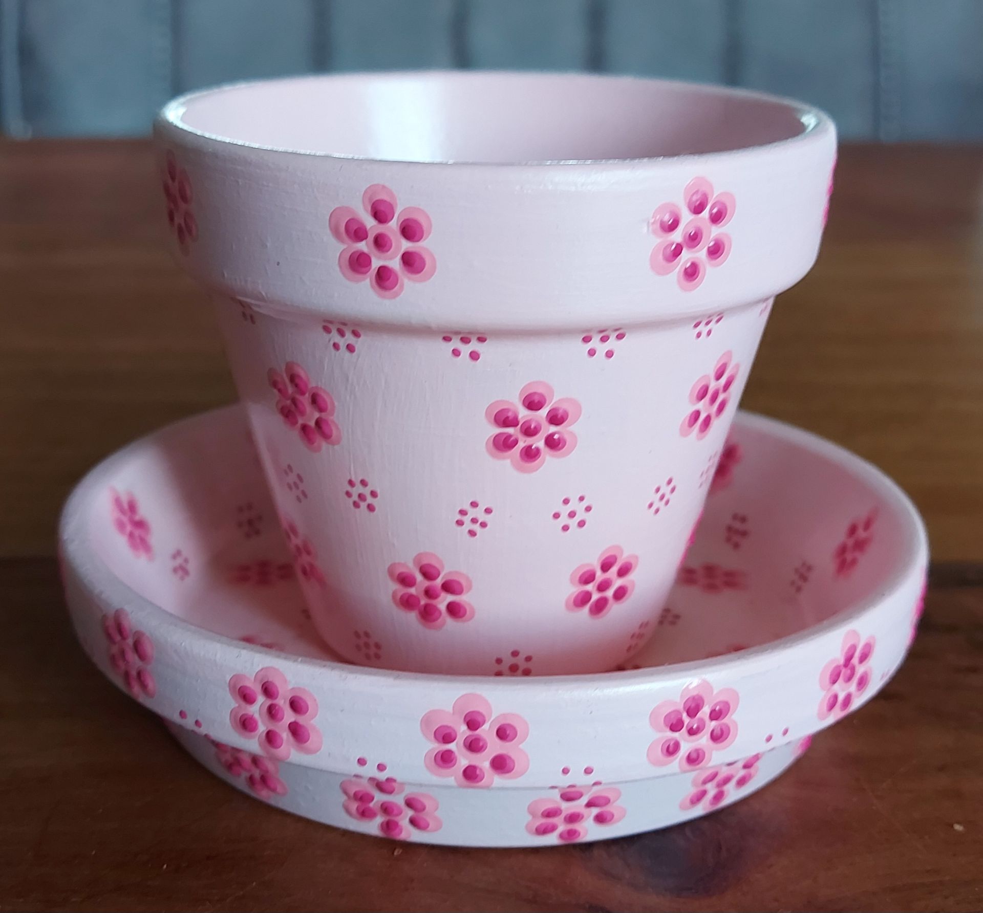 Roze bloempot met schotel, beschilderd met een roze bloemenpatroon.