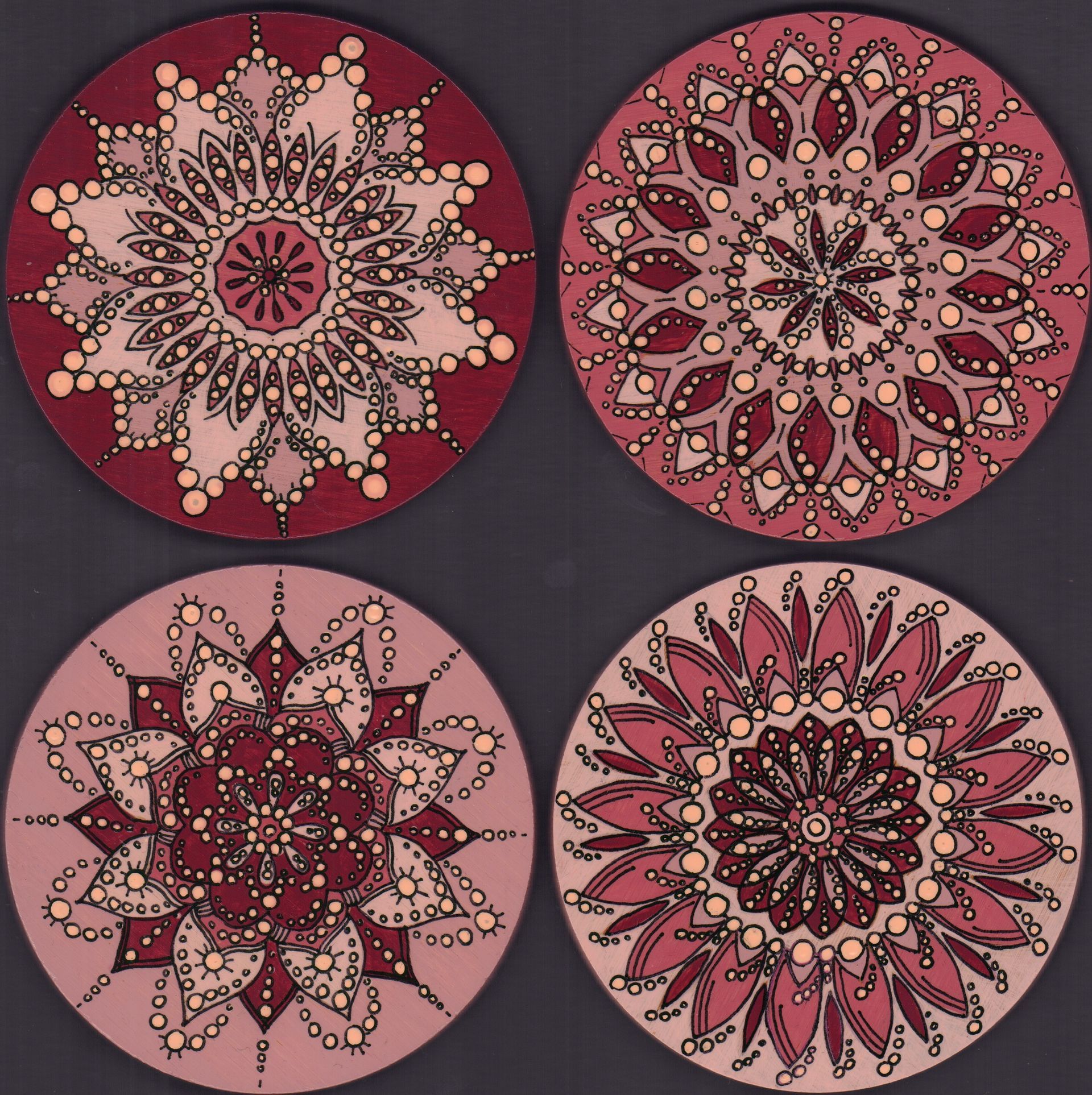Vier ronde onderzetters met rode en roze mandala-motieven.