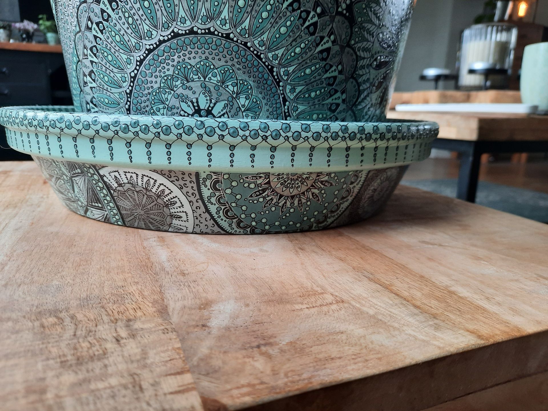 Twee decoratieve, turquoisekleurige keramische plantenpotten met patroon op een licht houten tafel.