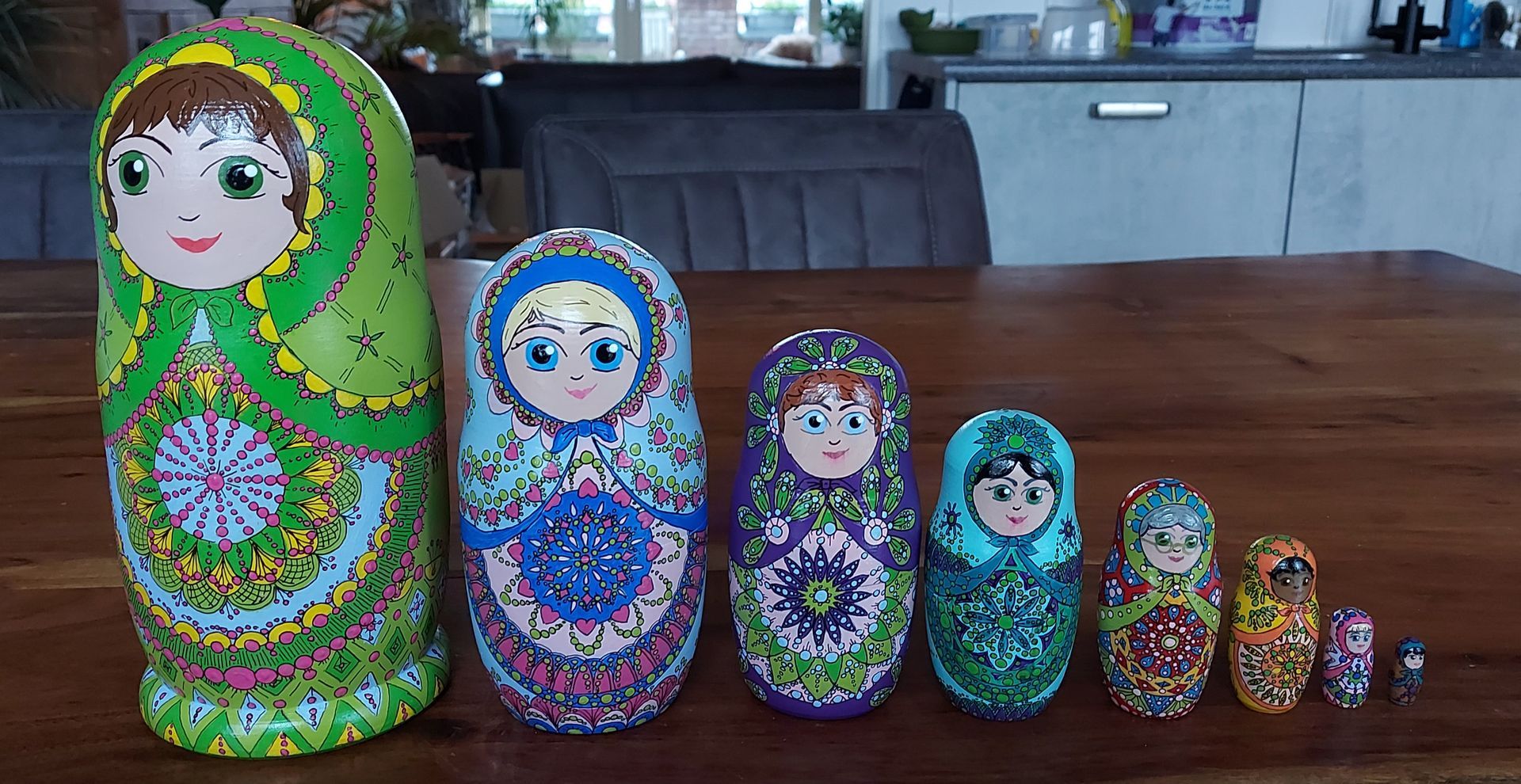 Een verzameling kleurrijke Matryoshka-poppen op een houten tafel, variërend in grootte van groot tot klein.
