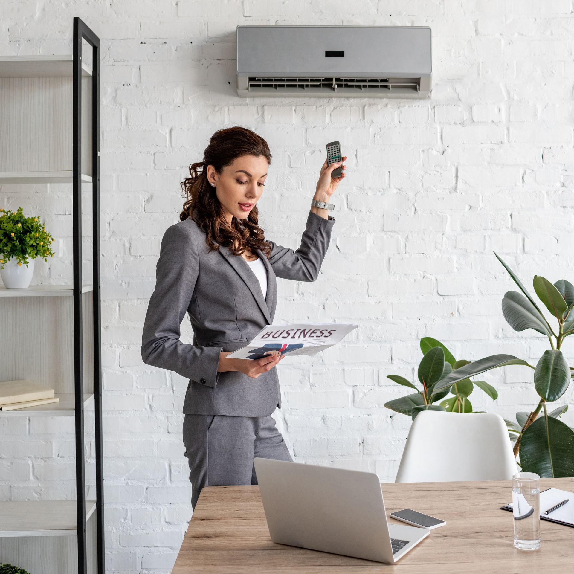 A woman in a suit is standing in front of a laptop computer.