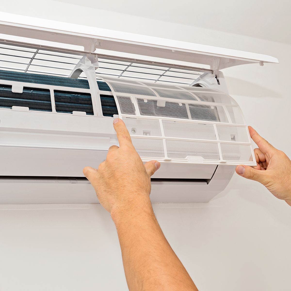 A person is cleaning the filter of an air conditioner.