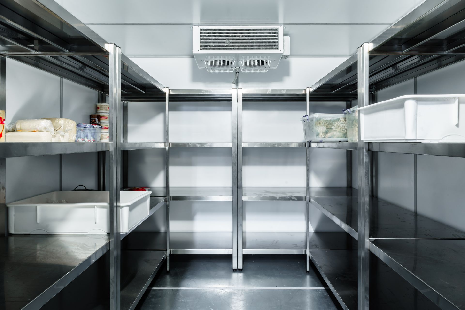 An empty refrigerator with stainless steel shelves in a kitchen.