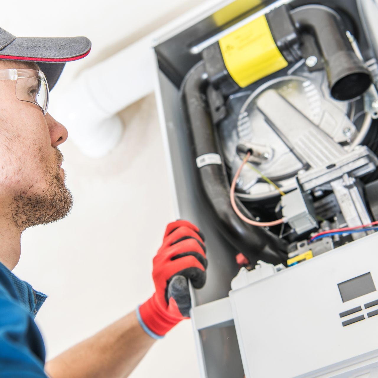 A man wearing red gloves is working on a machine.