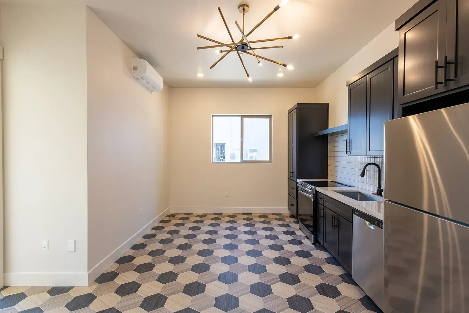 Kitchen with dark cabinets, stainless steel appliances, and patterned tile floor.