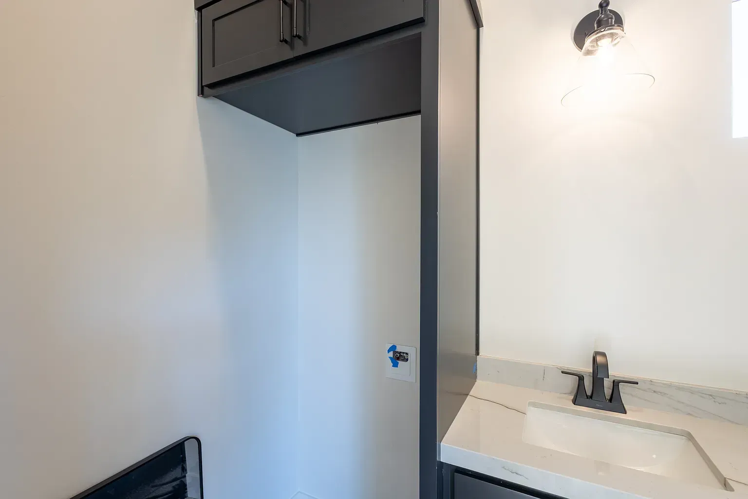 Bathroom with a white wall, black cabinets, and a sink.