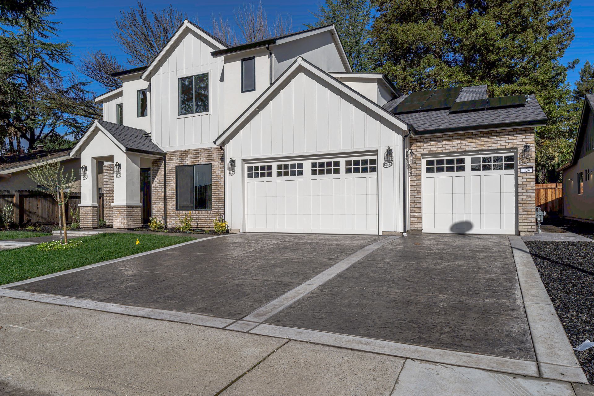 Modern two-story house with white siding, stone accents, and a concrete driveway.