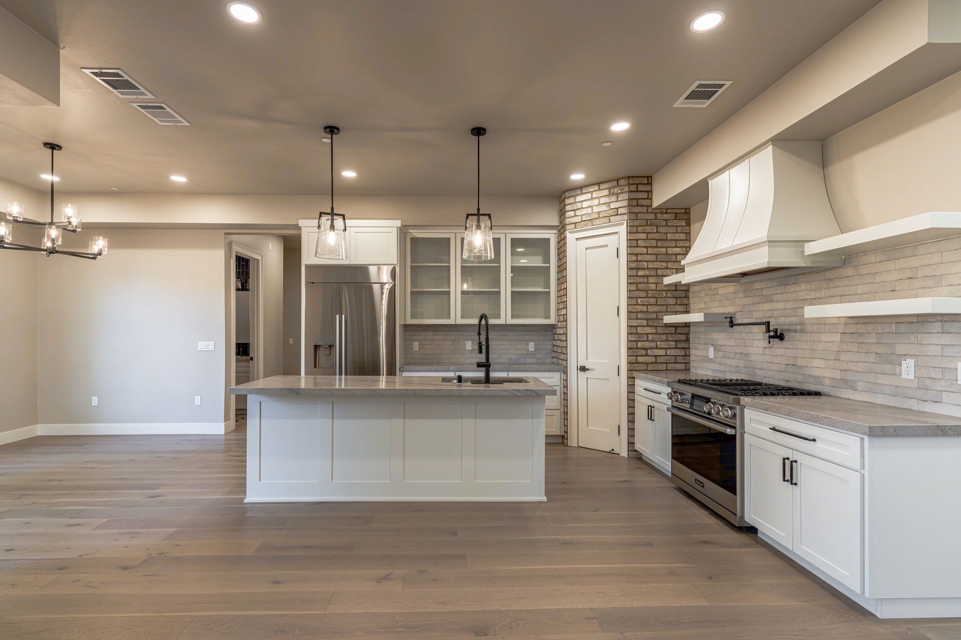 Spacious, modern kitchen with white cabinetry, stainless steel appliances, and a gray island.