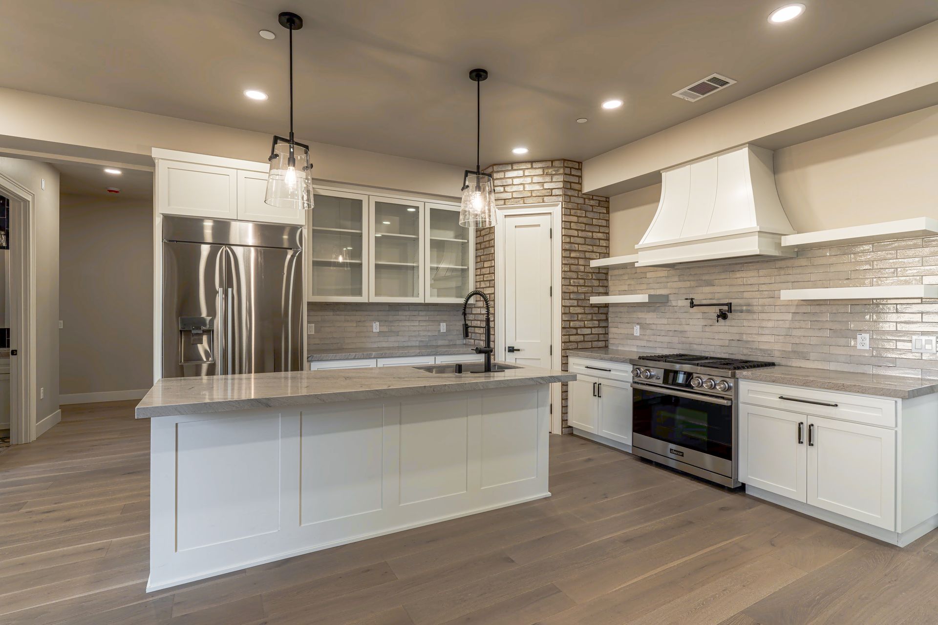 Modern kitchen with white cabinets, stainless steel appliances, and wood flooring.