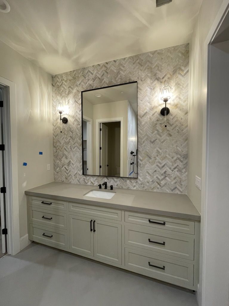 A bathroom with a sink , mirror and drawers.
