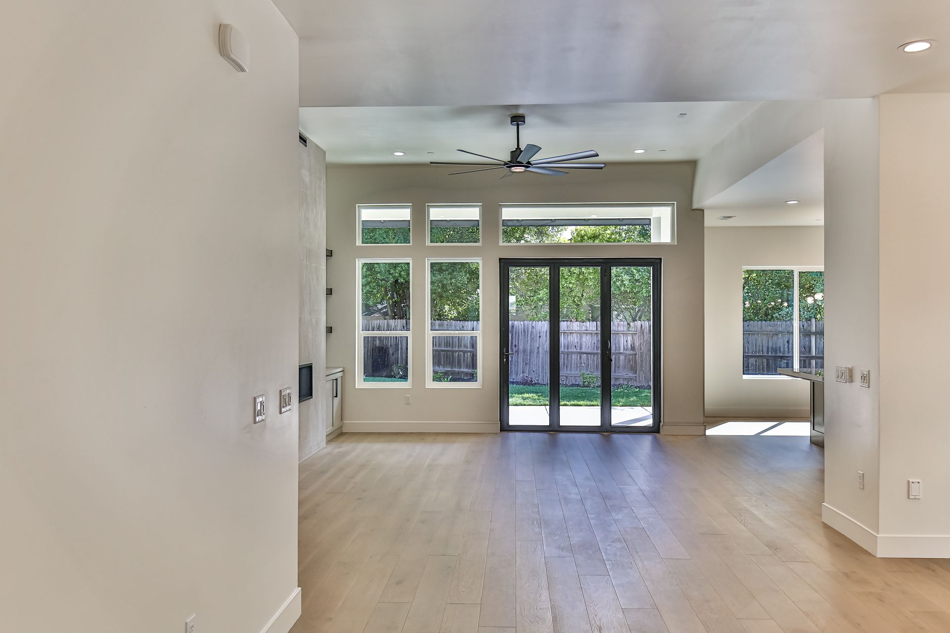 An empty room with a ceiling fan and sliding glass doors