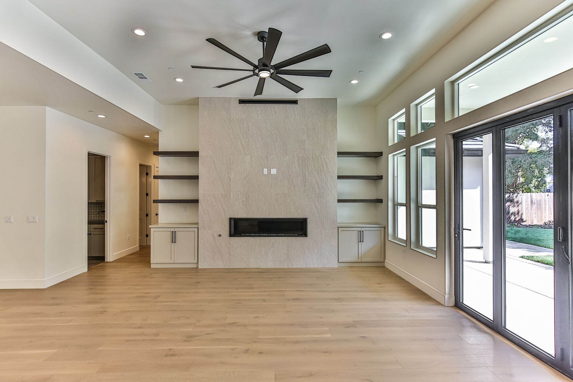 An empty living room with a fireplace and a ceiling fan.