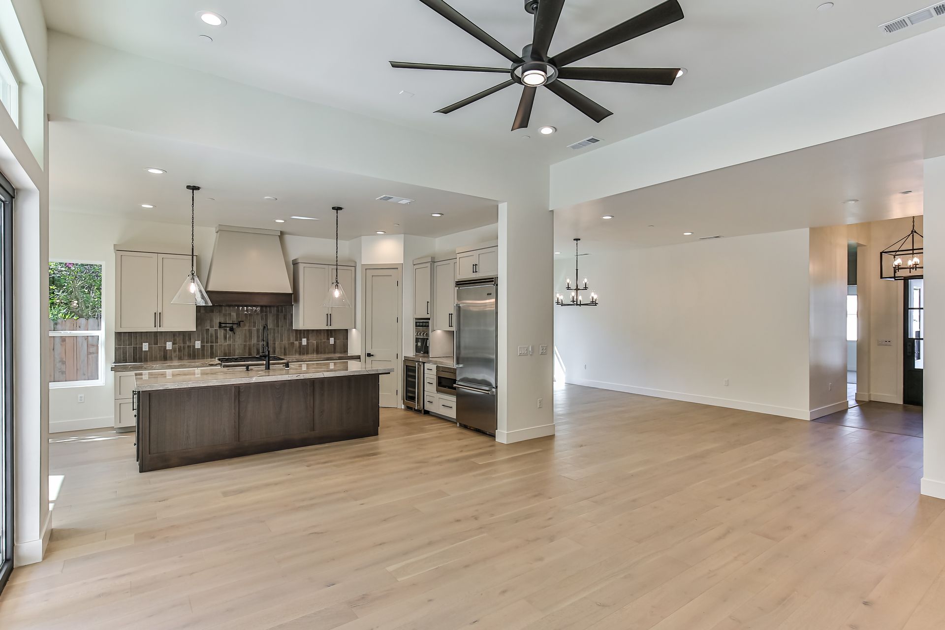There is a ceiling fan in the kitchen and a large island in the middle of the room.
