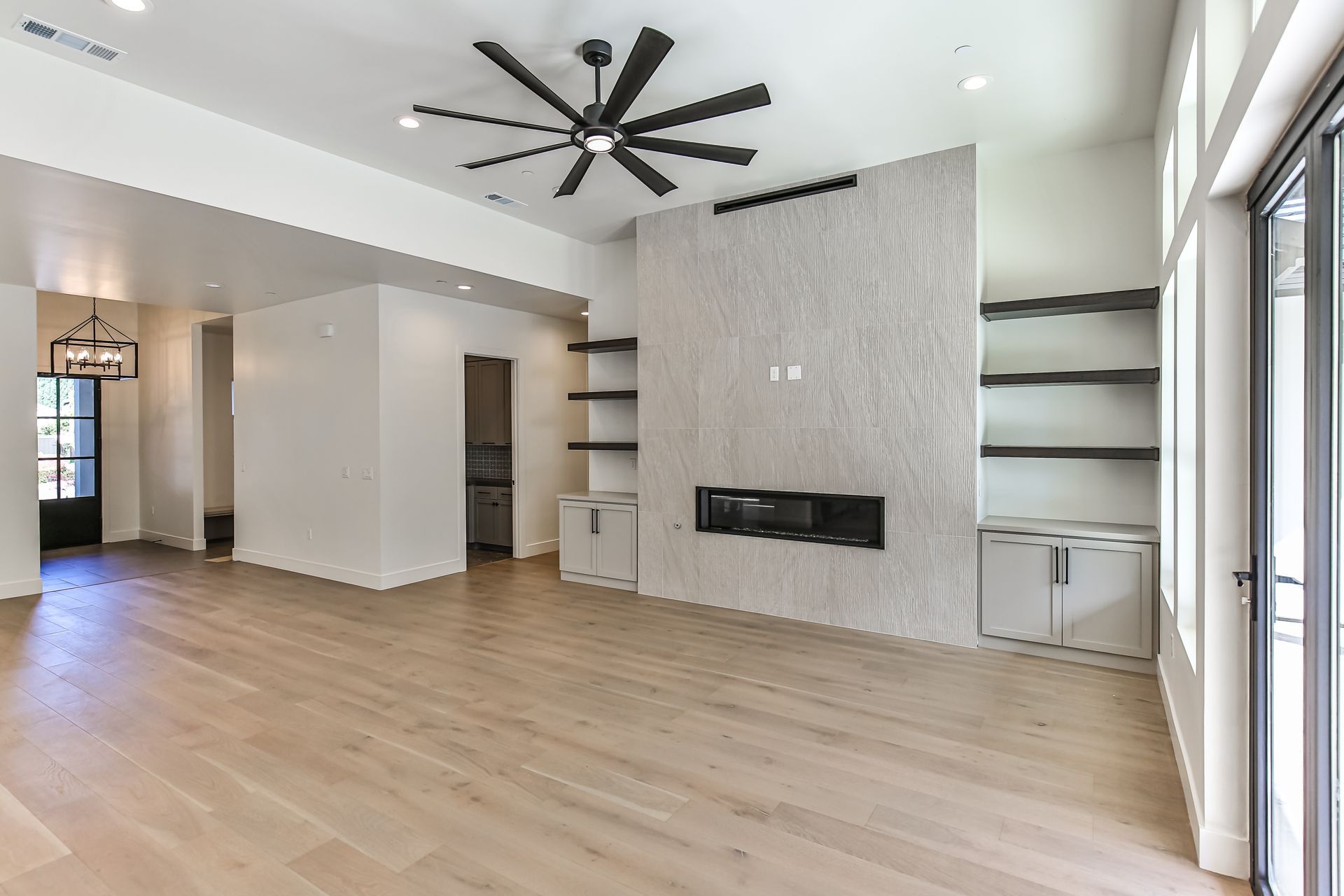 An empty living room with hardwood floors and a ceiling fan.