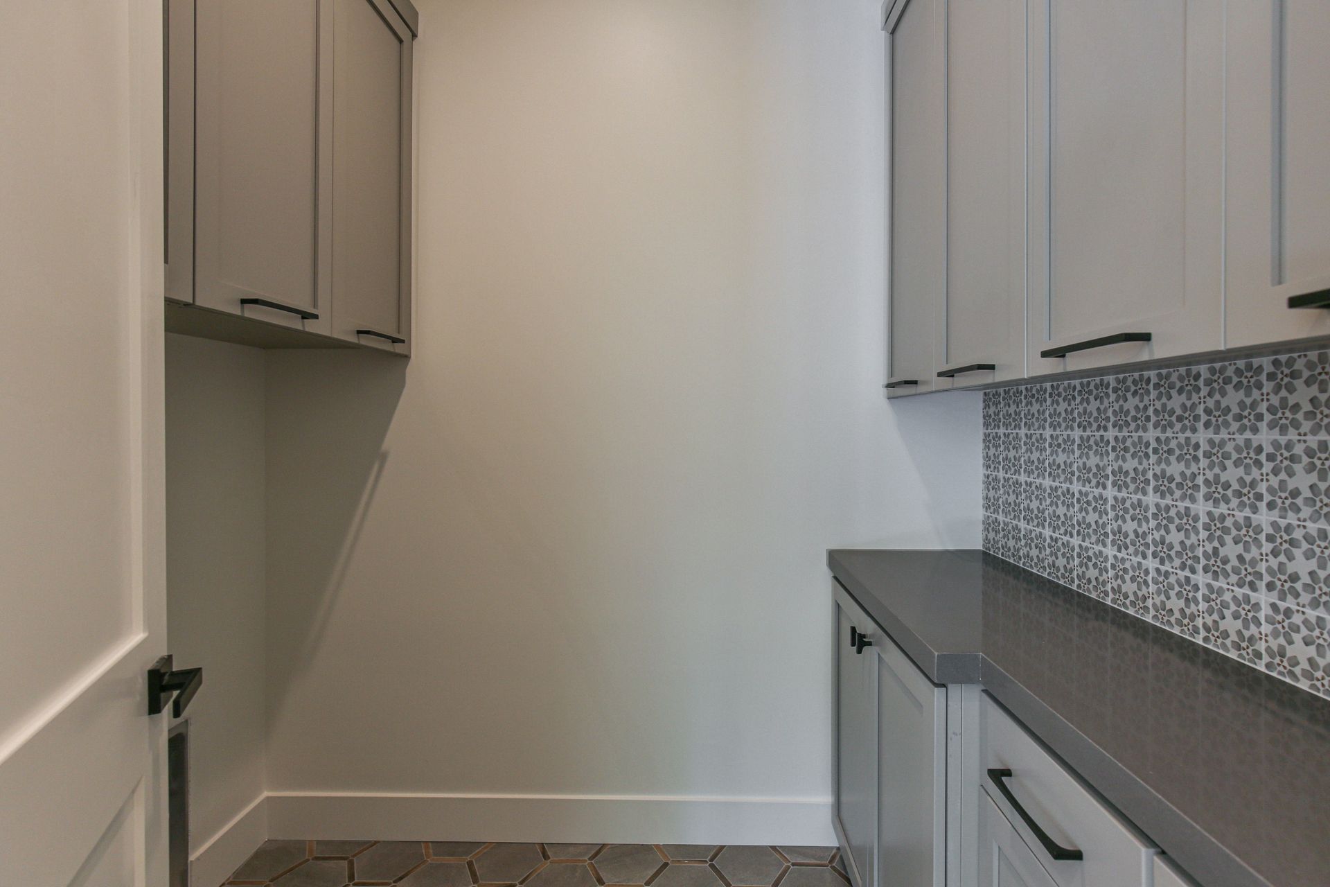 A laundry room with gray cabinets and a tiled floor.