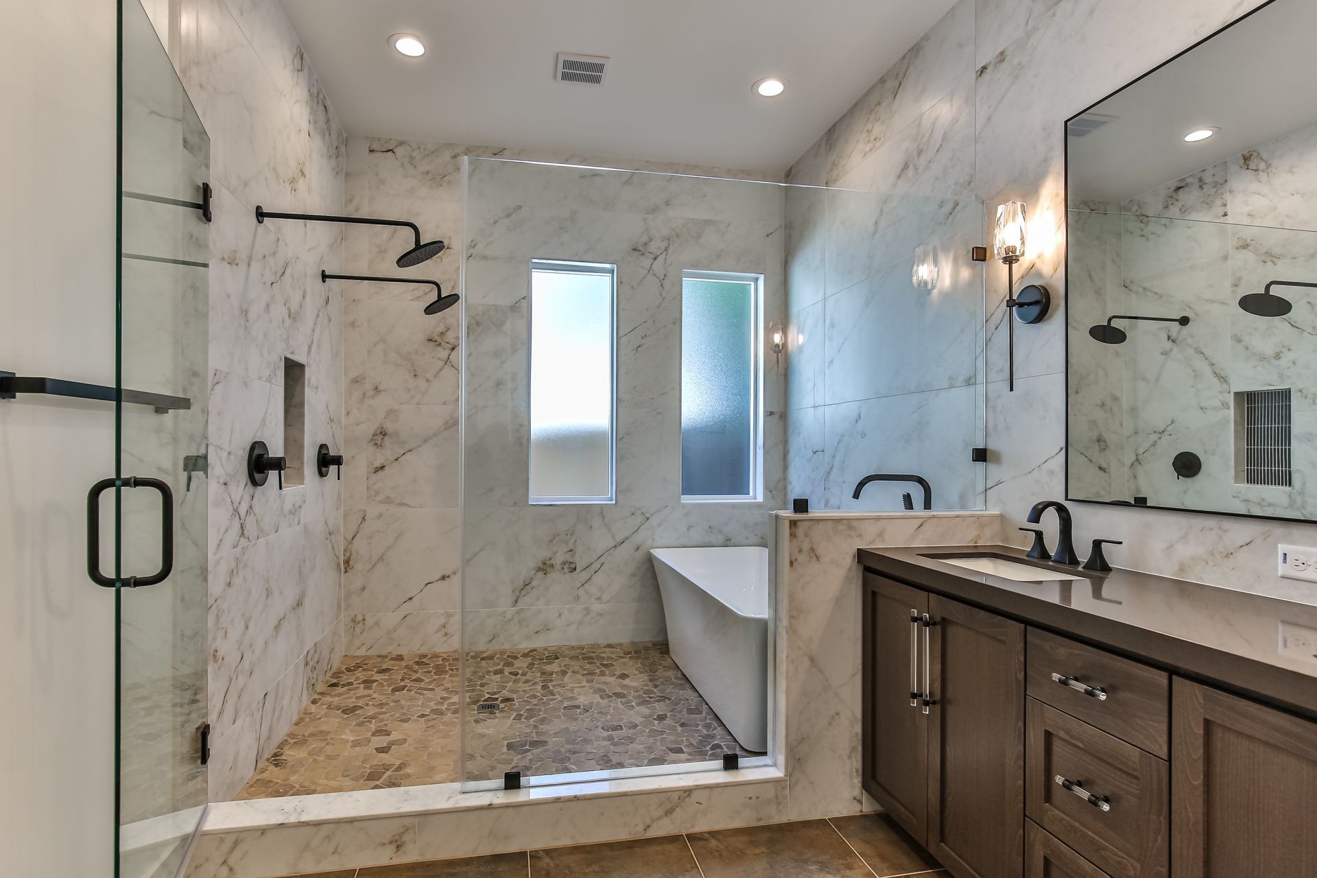 A bathroom with a walk in shower , tub , sink and mirror.