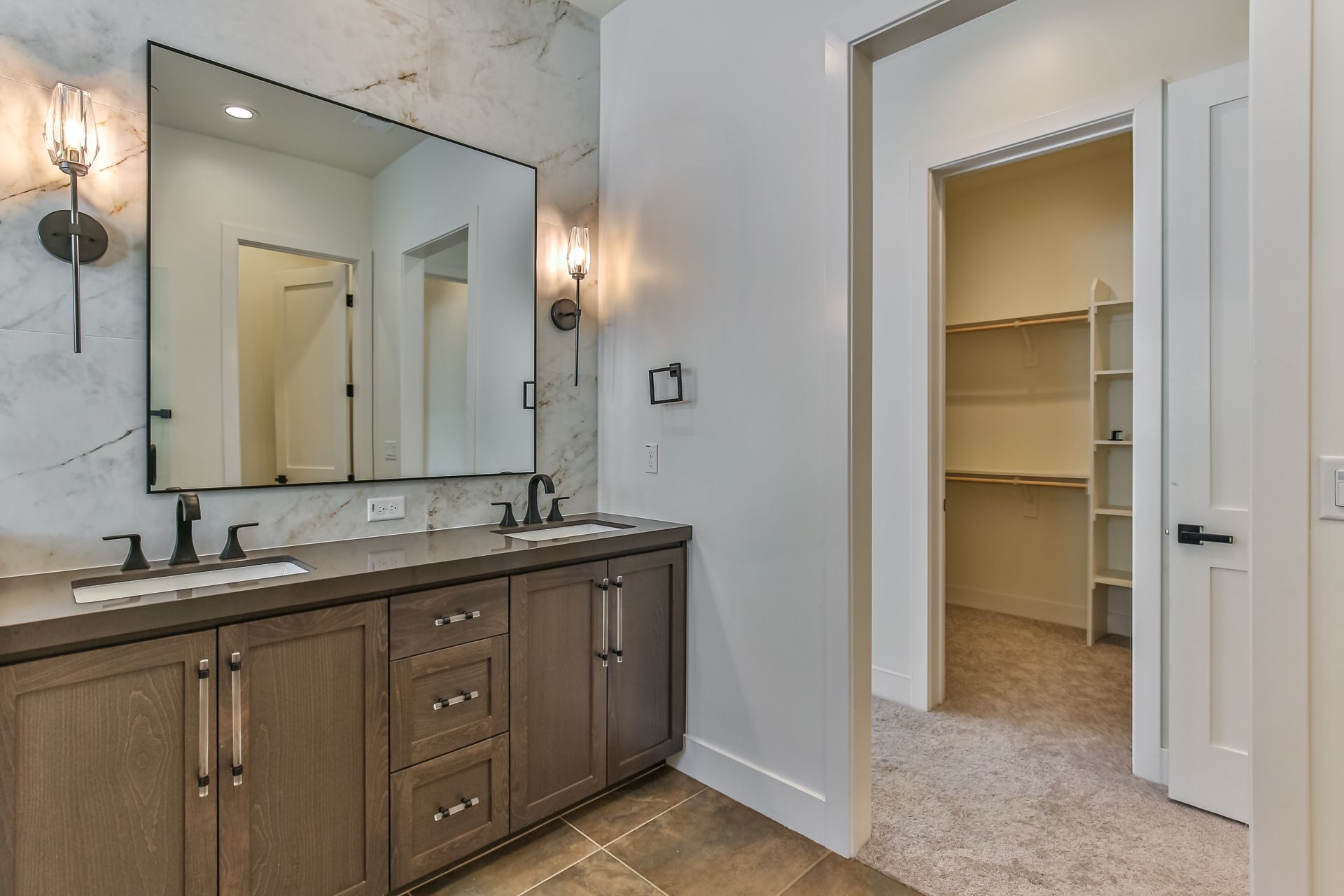 A bathroom with two sinks , a large mirror and a walk in closet.