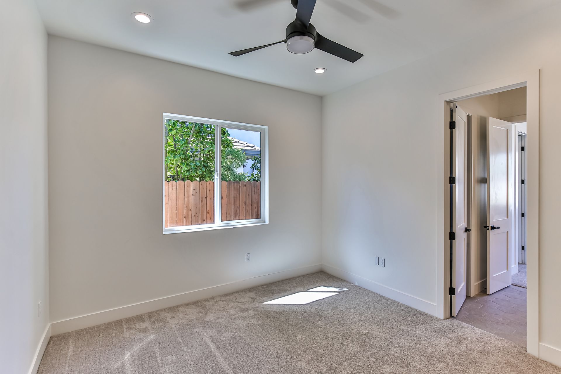 An empty bedroom with a ceiling fan and a window.