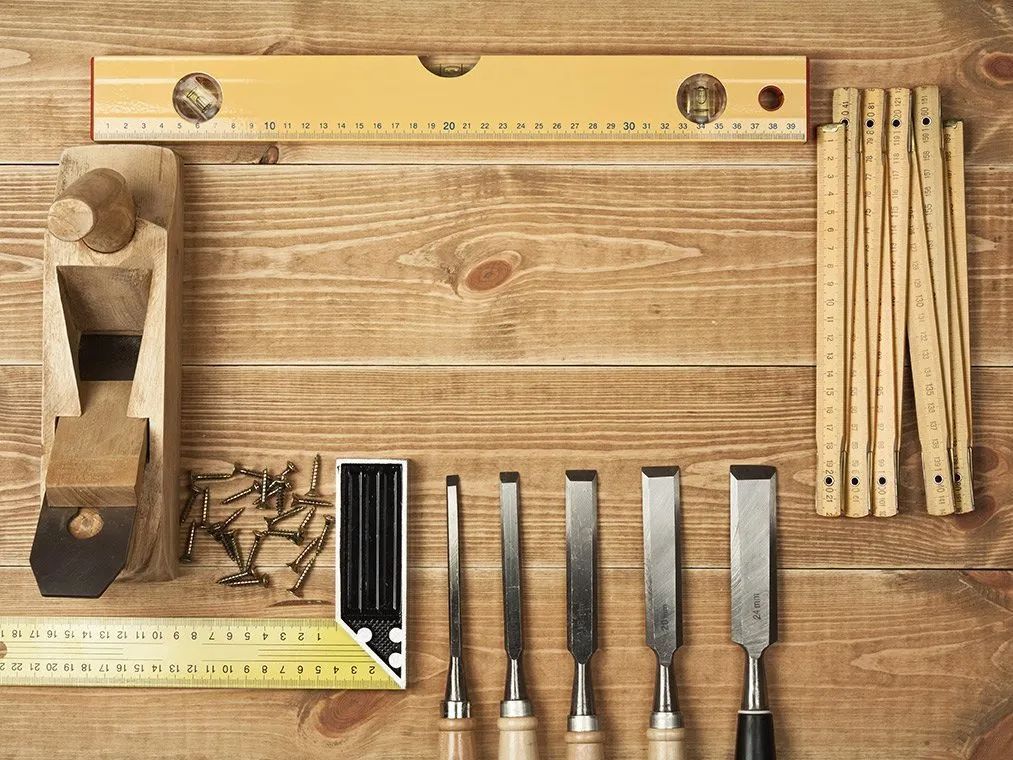 A wooden table with tools and a ruler on it