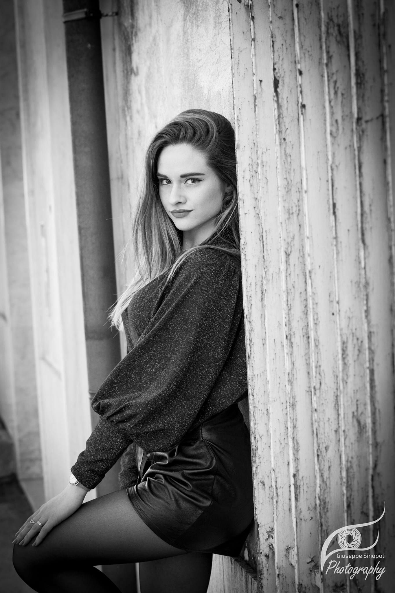 Una foto in bianco e nero di una donna appoggiata a un muro.