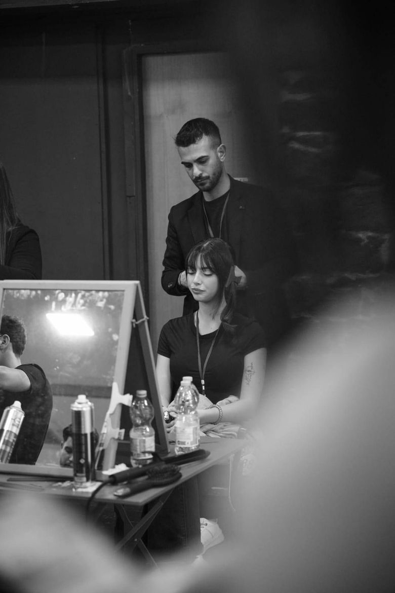 Un uomo si fa sistemare i capelli da una donna in una foto in bianco e nero.