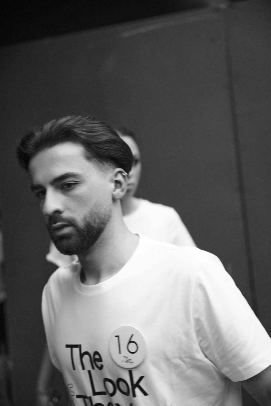 Un uomo con la barba che indossa una maglietta bianca con la scritta "look"