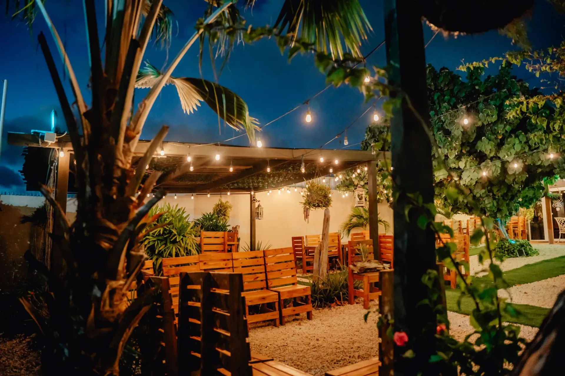 A patio with wooden pallets and string lights at night.