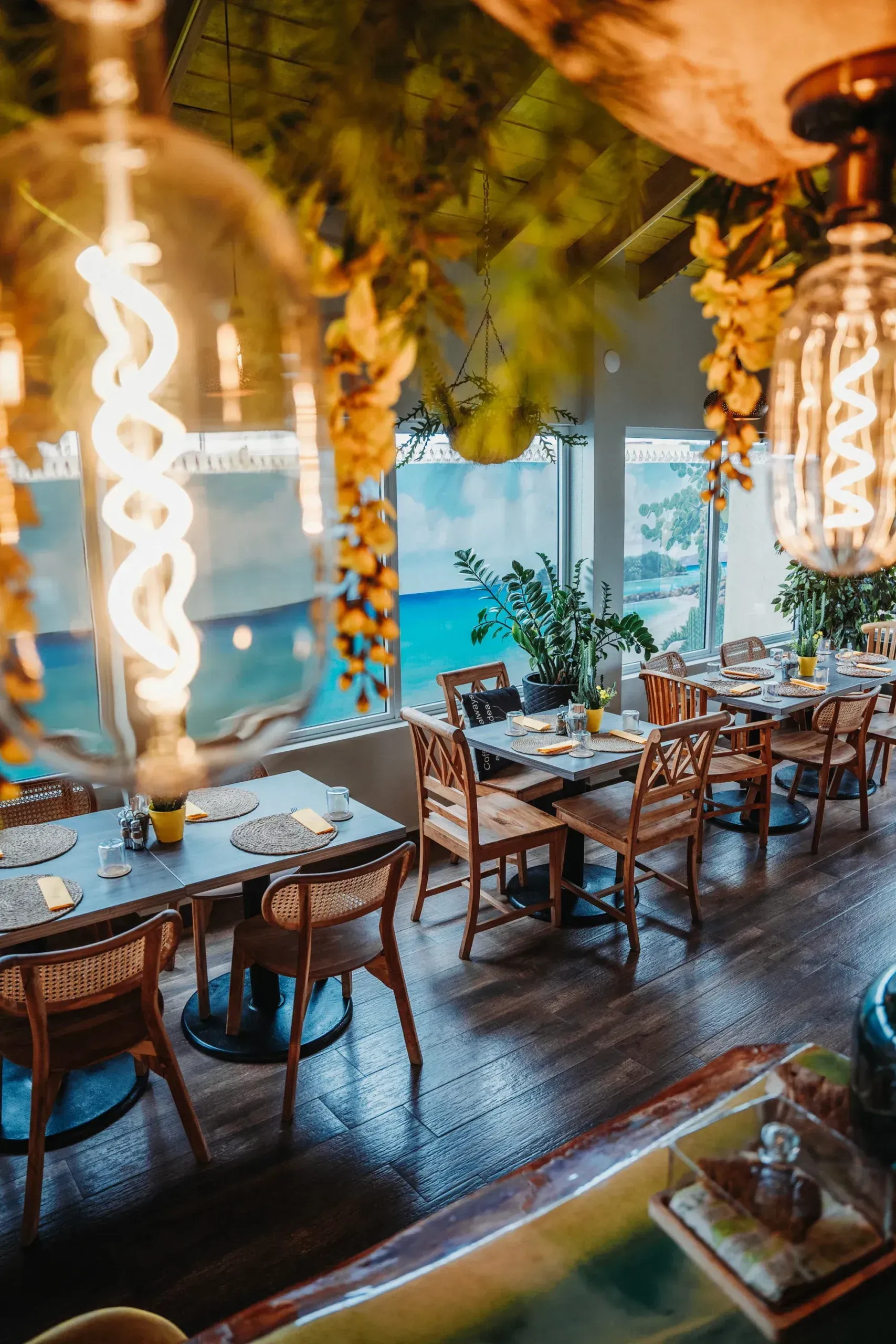 A restaurant with tables and chairs and a view of the ocean.